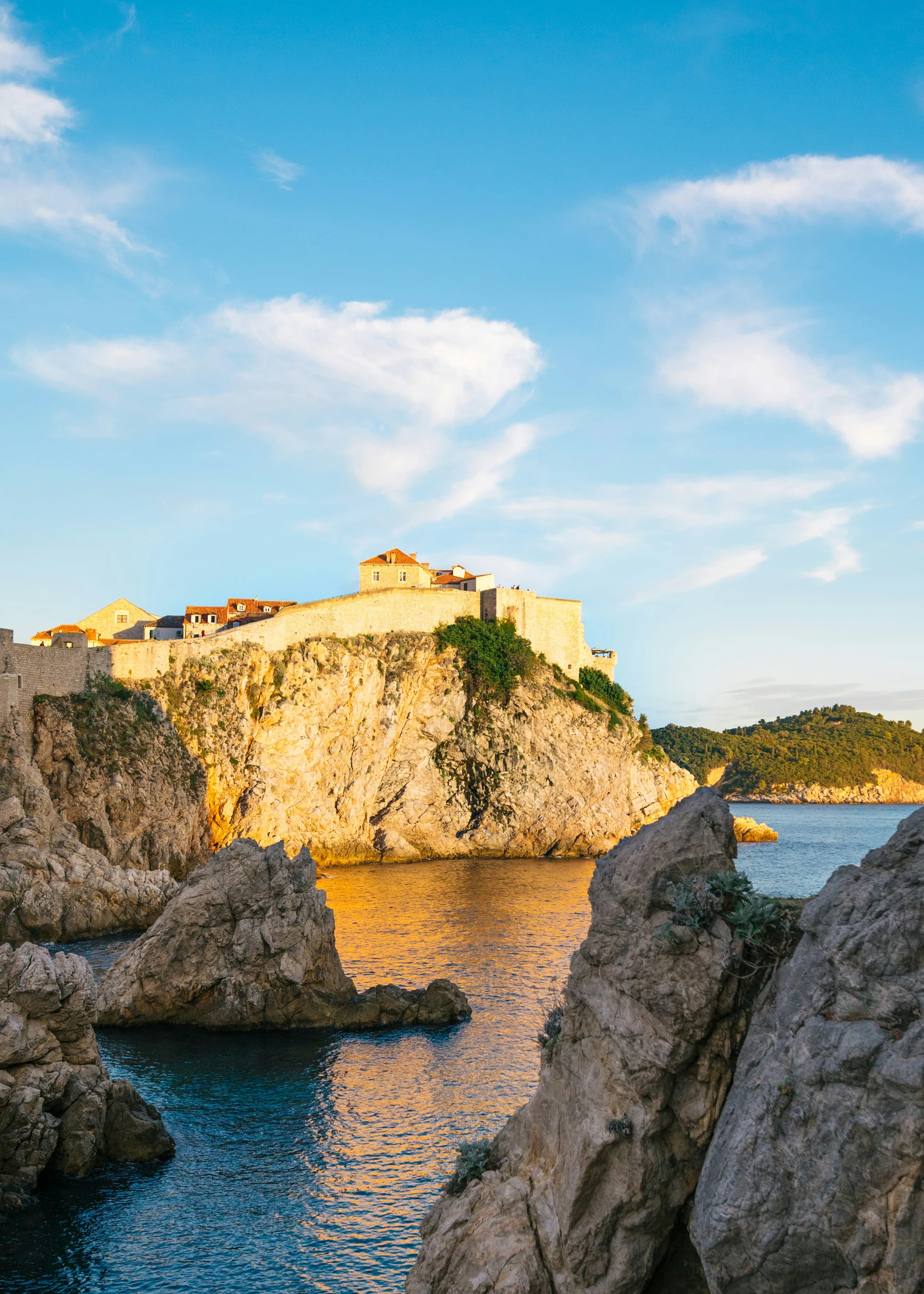 Dubrovniks goldene Steinmauern über einer felsigen Adriabucht bei Sonnenuntergang